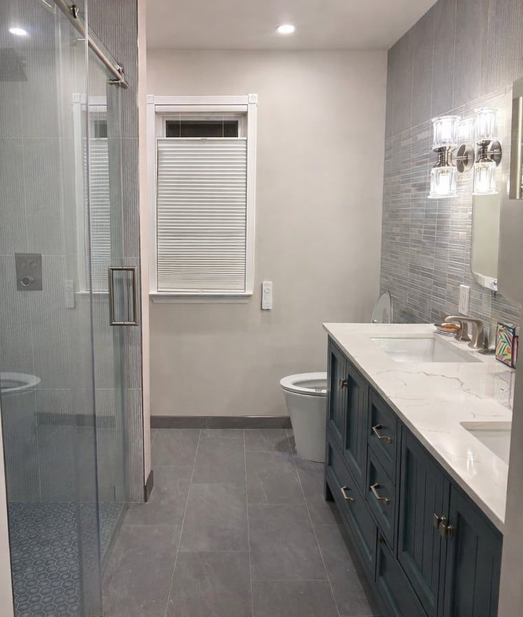 The same bathroom after: glass shower, navy vanity and gray plank tile